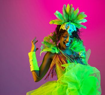 Woman smiling and dancing against a pink backdrop